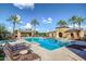 Beautiful community pool area with lounge chairs, a covered pavilion, and lush palm trees under a clear sky at 20423 W Springfield St, Buckeye, AZ 85396