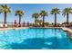 This is a scenic view of a community pool area with multiple lounge chairs, umbrellas, and palm trees for a resort-style feel at 20423 W Springfield St, Buckeye, AZ 85396