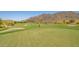 A sprawling golf course features rolling green hills with a desert landscape and mountain views for a scenic golfing experience at 20423 W Springfield St, Buckeye, AZ 85396