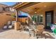 Inviting covered patio area featuring multiple seating areas, an outdoor fan, and neutral earth-tone pavers at 20423 W Springfield St, Buckeye, AZ 85396