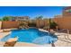 Backyard pool featuring waterfall and desert landscaping with blue handrail and brick patio at 20423 W Springfield St, Buckeye, AZ 85396