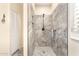 Bathroom shower with gray stone tile, rainfall showerhead, built-in shelving, and white closet doors at 20423 W Springfield St, Buckeye, AZ 85396