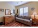 Versatile bedroom offering ample space, natural light with wood floors, dresser, sofa, and neutral color palette at 20581 N Enchantment Pass, Maricopa, AZ 85138