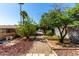 Backyard view featuring a walkway, garden beds, and mature trees, creating a peaceful outdoor space at 2114 E Hale St, Mesa, AZ 85213