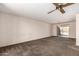 Spacious living room with plush carpeting, a ceiling fan, and glass doors leading to a bright, airy patio at 2114 E Hale St, Mesa, AZ 85213