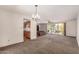 Large living room with cozy carpet, classic chandelier, and windows showcasing the lush backyard and desert scenery at 2114 E Hale St, Mesa, AZ 85213