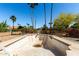 A fenced empty pool surrounded by desert trees and landscaping at 2114 E Hale St, Mesa, AZ 85213