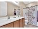 Bright bathroom featuring double sinks, wood cabinets, and floral shower curtain at 2189 W Mila Way, San Tan Valley, AZ 85144