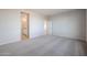 A spacious carpeted bedroom featuring an en-suite bathroom and a doorway leading to another room at 22045 N Rummler Ln, Maricopa, AZ 85138