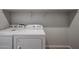 A well-lit laundry room featuring a washer and dryer, complemented by overhead shelving at 22045 N Rummler Ln, Maricopa, AZ 85138