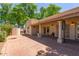 View of the backyard patio with red brick flooring, shade from large trees, and a stucco wall surround at 2322 S Rogers -- # 1, Mesa, AZ 85202