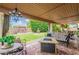 Cozy covered patio with chandelier, featuring a fire pit, comfortable seating, and view of the well-manicured lawn and fountain at 2369 W Shawnee Dr, Chandler, AZ 85224