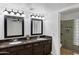 Double sink bathroom featuring granite counters, decorative mirrors and a tiled shower with a glass block window at 2633 S El Dorado Dr, Mesa, AZ 85202