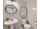 Stylish powder room featuring a pedestal sink, round mirror, and modern black and white patterned floor at 3555 E Morenci Rd, San Tan Valley, AZ 85143