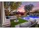 Inviting backyard features comfortable seating, lush landscaping, ambient lighting, and a sparkling pool perfect for relaxation at 3641 E Los Gatos Dr, Phoenix, AZ 85050