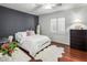 Bedroom with accent wall, hardwood floors, white bedding, and bright window at 3641 E Los Gatos Dr, Phoenix, AZ 85050