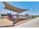 Community playground featuring shaded play structures and covered picnic area, perfect for outdoor fun and relaxation at 36525 W Maddaloni Ave, Maricopa, AZ 85138