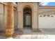 Close-up of the front door framed by an archway, desert landscaping, and a two-car garage at 3711 E Long Lake Rd, Phoenix, AZ 85048
