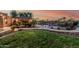 Large backyard with grassy areas, a pool with waterfalls, and a covered patio with a kitchen and dining area at 3754 E Flintlock Dr, Queen Creek, AZ 85142