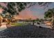 Extensive backyard with a pool, outdoor kitchen, fire pit, landscaped areas, all under a sunset sky at 3754 E Flintlock Dr, Queen Creek, AZ 85142
