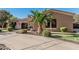 A beautiful desert home with lush landscaping, a circular driveway, and a gated stone archway entrance at 3754 E Flintlock Dr, Queen Creek, AZ 85142