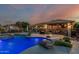 An outdoor area with a pool, diving board, hot tub and outdoor kitchen under a beautiful sunset sky at 3754 E Flintlock Dr, Queen Creek, AZ 85142