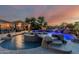 Outdoor pool area featuring a waterfall, diving board, hot tub and outdoor kitchen under sunset sky at 3754 E Flintlock Dr, Queen Creek, AZ 85142
