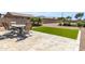 Nice backyard featuring a stone patio, a table with four chairs, artificial grass, and desert landscaping at 41769 W Canasta Ln, Maricopa, AZ 85138