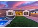 Beautiful backyard featuring pool, lush green grass, and covered patio with string lights at sunset at 5228 S 106Th Pl, Mesa, AZ 85212