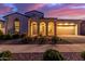 Charming home exterior features arched entryway, desert landscaping, and warm lighting against a colorful dusk sky at 5228 S 106Th Pl, Mesa, AZ 85212