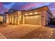 Home exterior showcases a spacious two-car garage, brick driveway, and stucco facade under a twilight sky at 5228 S 106Th Pl, Mesa, AZ 85212