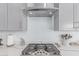 Close-up of the modern kitchen's gas range and stainless steel range hood, complemented by sleek countertops at 5228 S 106Th Pl, Mesa, AZ 85212