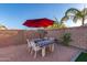 Charming outdoor dining area with a red umbrella, patterned tablecloth, and string lights, perfect for entertaining guests at 5228 S 106Th Pl, Mesa, AZ 85212
