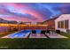 Sparkling pool and spa with lounge chairs, lush green lawn, and vibrant sunset in the background at 5228 S 106Th Pl, Mesa, AZ 85212
