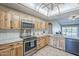 A spacious kitchen with light wood cabinets, stainless steel appliances, and a ceiling fan at 5944 W Greenbriar Dr, Glendale, AZ 85308