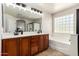 Bathroom with double sinks and vanity adjacent to tub with glass block window at 5973 S Legend Dr, Gilbert, AZ 85298