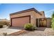 Side view of a two-car garage featuring a pink door, with desert landscaping and a wooden gate at 6203 W Caribe Ln, Glendale, AZ 85306