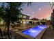 A beautiful backyard showcases a pool, patio, lush landscaping, and ambient lighting at 6449 S Glory Ct, Gilbert, AZ 85298