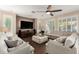 Comfortable living room with a ceiling fan, hardwood floors, a large sectional couch, and a large television at 6449 S Glory Ct, Gilbert, AZ 85298
