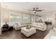 Open concept living room with hardwood floors, a large sectional couch, and easy access to the kitchen at 6449 S Glory Ct, Gilbert, AZ 85298