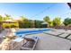 View of a serene pool area with lounge chairs, a patio umbrella, and lush greenery at 6449 S Glory Ct, Gilbert, AZ 85298