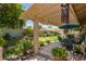 Relaxing backyard patio shaded by a pergola, surrounded by colorful flowers and greenery at 7185 W Kimberly Way, Glendale, AZ 85308