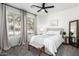 Neutral bedroom showcasing serene decor, a ceiling fan, and sun-drenched windows with views to the outdoors at 7236 W Aurora Dr, Glendale, AZ 85308