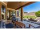 Relaxing covered patio with lounge furniture, a BBQ grill, and a view of the backyard's fire pit and lush lawn at 7236 W Aurora Dr, Glendale, AZ 85308