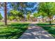 Scenic park view featuring a paved pathway, lush green grass, mature trees and shaded playground equipment at 7236 W Aurora Dr, Glendale, AZ 85308