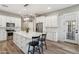 Bright kitchen with white cabinets, stainless steel appliances, island with seating, and wood flooring at 11013 E Decatur St, Mesa, AZ 85207