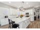Bright kitchen with white cabinets, stainless steel appliances, island with seating, and wood flooring at 11013 E Decatur St, Mesa, AZ 85207