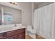 Well-lit bathroom featuring a vanity with dark wood cabinets and a shower-tub combo with a white shower curtain at 11040 E Nichols Ave, Mesa, AZ 85209