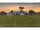 Expansive backyard featuring lush green grass, mature trees, and a charming single-story home at sunset at 1551 E Longhorn Dr, Chandler, AZ 85286