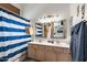 Well-lit bathroom with a double sink vanity, framed mirrors, and a bathtub with a striped shower curtain at 17424 N 1St Ave, Phoenix, AZ 85023